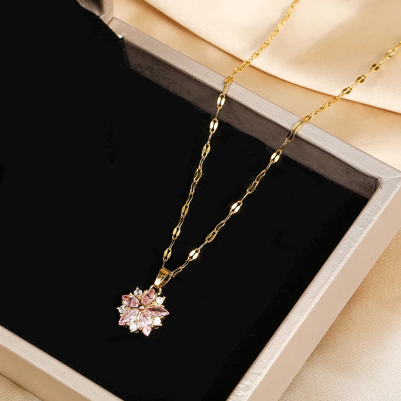 Pendentif fleur de cerisier doré posé sur le velours noir d'un écrin ouvert.