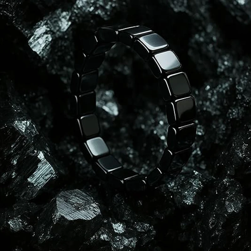 Bracelet d'hématite posé sur une pierre sombre, reflets métalliques