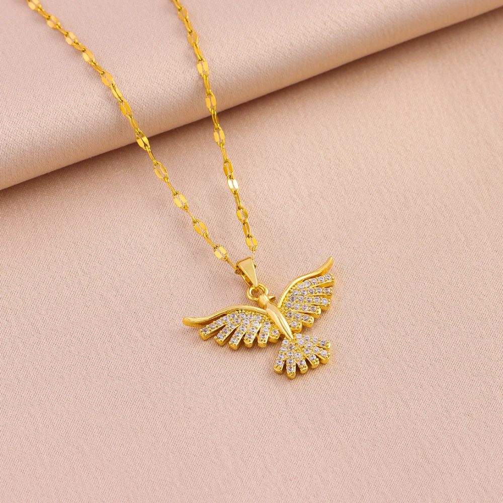 Le collier à pendentif oiseau posé sur un tissu rose poudré, ailes relevées et queue en éventail.