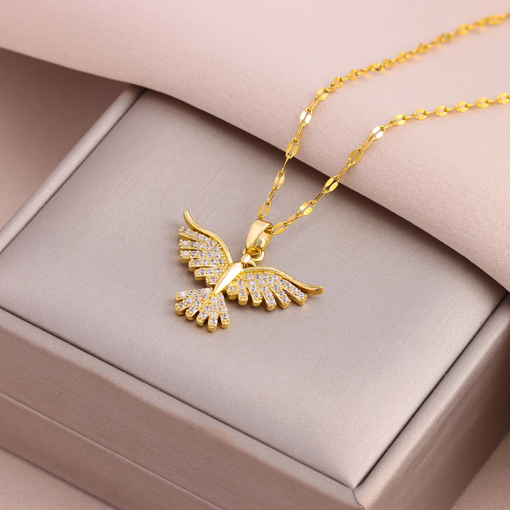 Pendentif oiseau doré aux ailes pavées de zircons blancs, présenté dans son écrin.