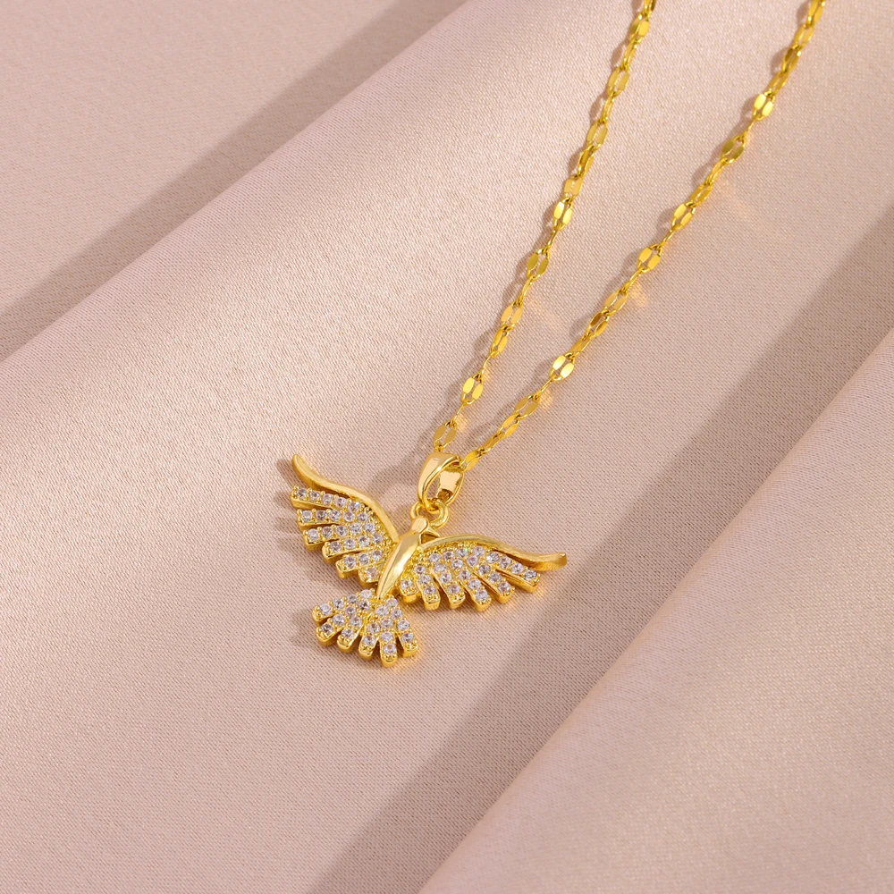 Le collier à pendentif oiseau déployé sur un drapé rose, chaîne fine à maillons plats.